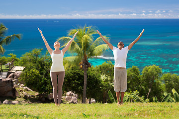 Image showing happy couple making yoga exercises on beach