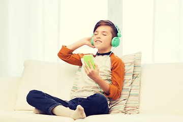 Image showing happy boy with smartphone and headphones at home