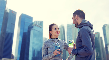 Image showing smiling couple with bottles of water outdoors