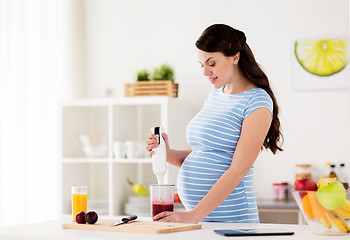 Image showing pregnant woman with blender cooking fruits at home