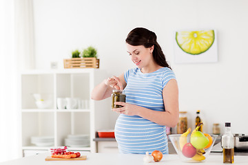 Image showing pregnant woman eating pickles at home kitchen