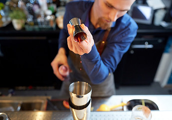 Image showing bartender with shaker preparing cocktail at bar