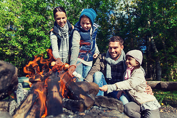 Image showing happy family roasting marshmallow over campfire