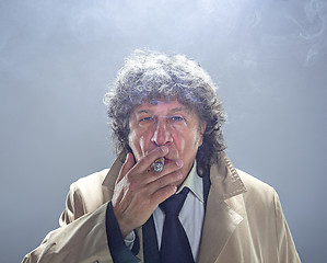 Image showing The senior man with cigar as detective or boss of mafia on gray studio background