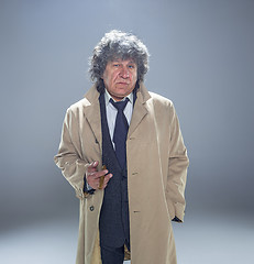 Image showing The senior man with cigar as detective or boss of mafia on gray studio background