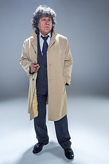 Image showing The senior man with cigar as detective or boss of mafia on gray studio background