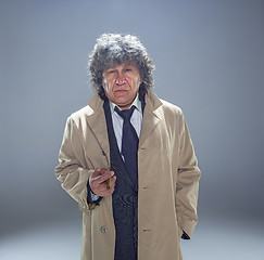 Image showing The senior man with cigar as detective or boss of mafia on gray studio background