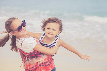 Image showing Sister and brother playing on the beach at the day time.