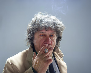 Image showing The senior man with cigar as detective or boss of mafia on gray studio background