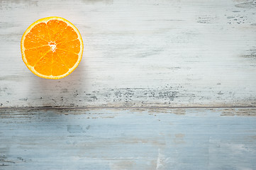 Image showing One slice of fresh oranges on painted wooden board