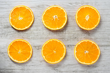 Image showing Six slices of fresh oranges on white wood background