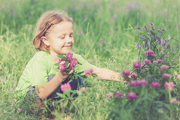 Image showing Cute little boy  playing with flowers in  park