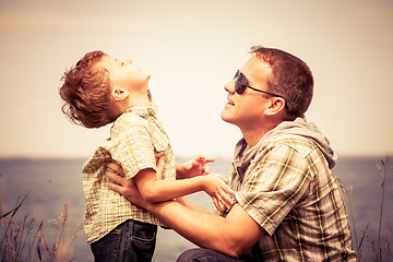 Image showing Father and son playing at the park near lake at the day time.