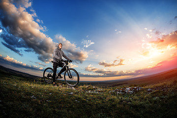 Image showing Young man cycling on a rural road through meadow