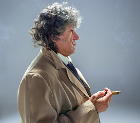 Image showing The senior man with cigar as detective or boss of mafia on gray studio background