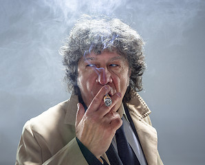 Image showing The senior man with cigar as detective or boss of mafia on gray studio background