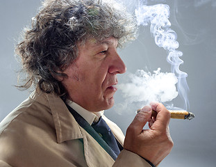 Image showing The senior man with cigar as detective or boss of mafia on gray studio background