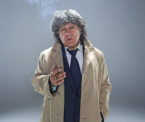 Image showing The senior man with cigar as detective or boss of mafia on gray studio background