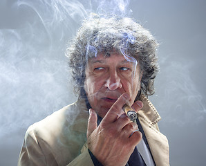 Image showing The senior man with cigar as detective or boss of mafia on gray studio background