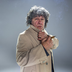 Image showing The senior man with cigar as detective or boss of mafia on gray studio background