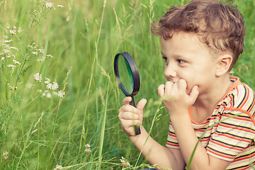 Image showing Happy little boy exploring nature with magnifying glass