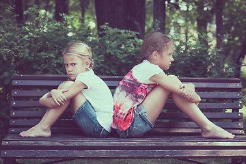 Image showing two sad sister sitting on the bench in park