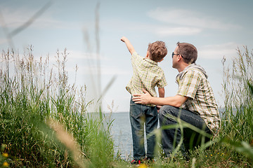 Image showing Father and son playing at the park near lake at the day time.