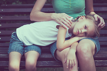 Image showing Sad mother and daughter sitting on bench in the park