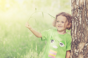 Image showing Cute little boy  playing with flowers in  park