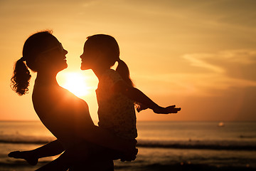 Image showing Mother and daughter playing on the beach at the sunset time.