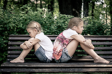 Image showing two sad sister sitting on the bench in park