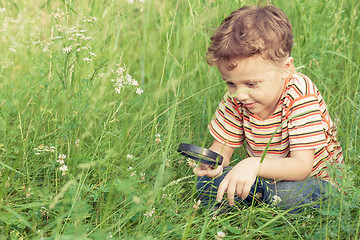 Image showing Happy little boy exploring nature with magnifying glass