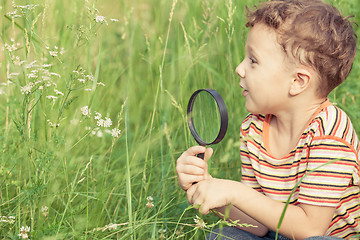 Image showing Happy little boy exploring nature with magnifying glass