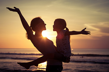 Image showing Mother and daughter playing on the beach at the sunset time. 