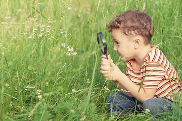 Image showing Happy little boy exploring nature with magnifying glass