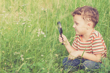 Image showing Happy little boy exploring nature with magnifying glass