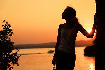 Image showing Silhouette of happy woman who standing on the coast of lake