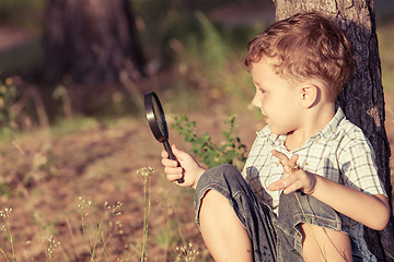 Image showing Happy little boy exploring nature with magnifying glass