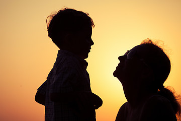 Image showing Mother and son playing on the beach at the sunset time.