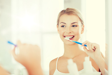 Image showing woman with toothbrush cleaning teeth at bathroom