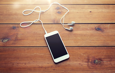 Image showing close up of blank smartphone and earphones on wood