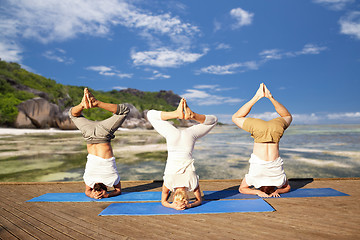 Image showing people making yoga headstand on mat outdoors