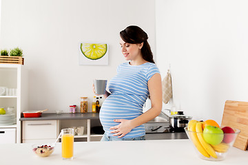 Image showing happy pregnant woman with cup at home kitchen