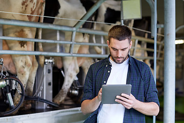 Image showing young man with tablet pc and cows on dairy farm