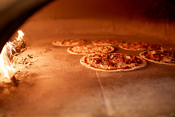 Image showing pizza baking in oven at pizzeria