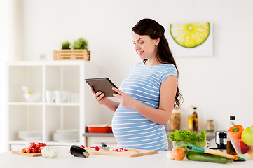 Image showing pregnant woman with tablet pc cooking at home