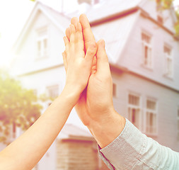 Image showing father and child hands making high five over house