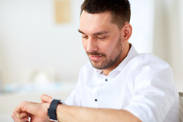 Image showing close up of businessman with smartwatch at office