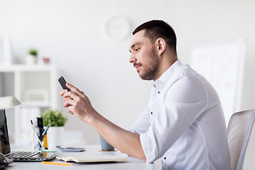 Image showing businessman with smartphone and notebook at office