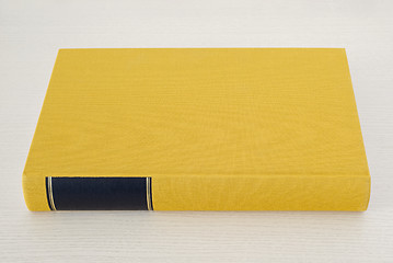 Image showing Yellow book with black frame on spine on the table